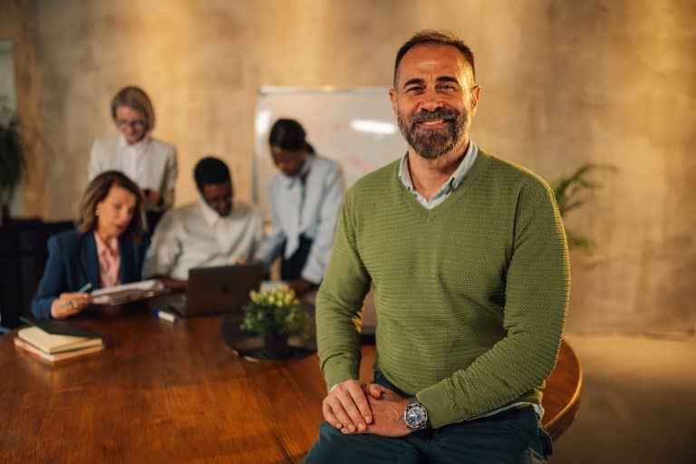 Smilende leder med medarbejdere i baggrunden der arbejder
